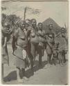 Group of women with children, hut in background