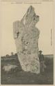 Man standing next to stone monument