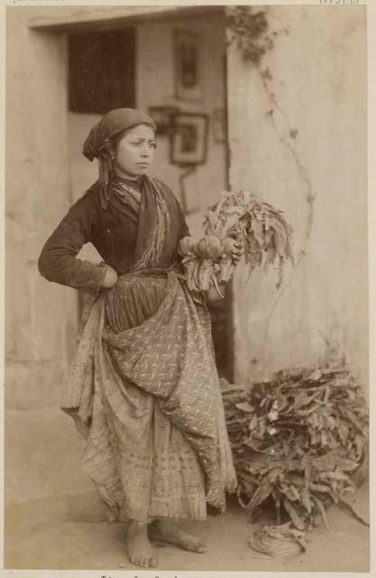 Woman standing and holding artichokes, doorway in background