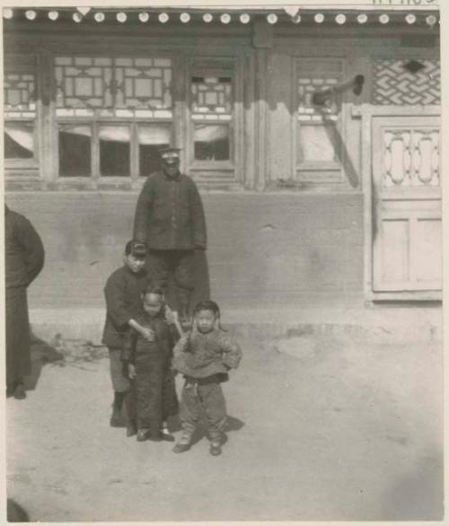 Three small girls and officer outside inn