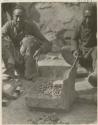 Two men making a stove out of a standard oil can