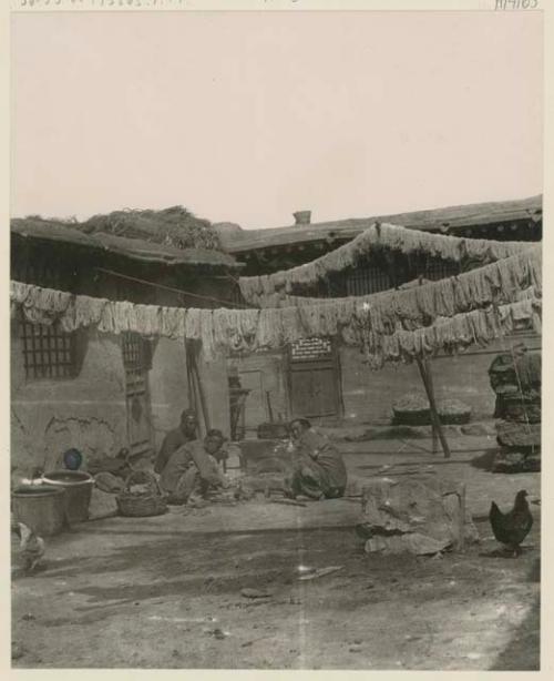 Three men in courtyard of carpet factory