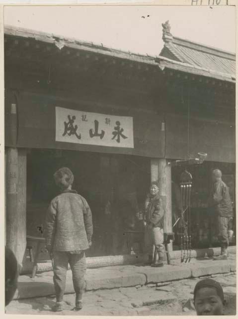 Men outside pipe and tobacco shop with pipe model hanging from roof