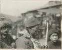 Native soldier holding stick and wearing hat