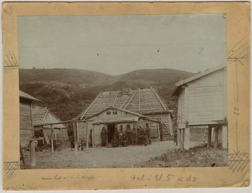 Group of people with dog in front of a hut