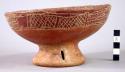 Purplish-red on red ring base vessel with incised band.  Slits on base.