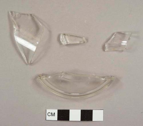 Colorless curved glass fragments, including one lid fragment and one possibly from a chamber pot or other vessel with flat rim