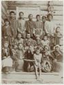 Group of men, women, and children on porch of building