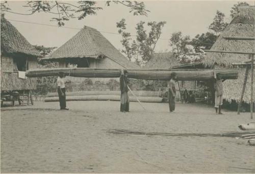 Four men carrying bamboo