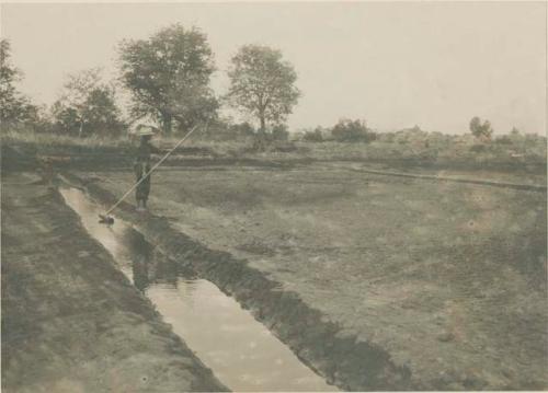 Man dipping up sea water to sprinke it over an evaporating bed