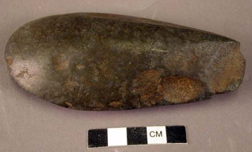 Ground stone axe, smooth on one side, pitted on the other