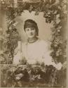 Woman with jug seen through decorative window