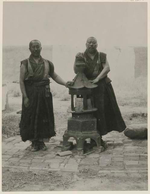 Two lamas standing next to an incense burner at the Little Poplar Tree Temple