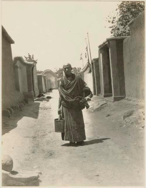 Young lama carrying pail of boiling tea