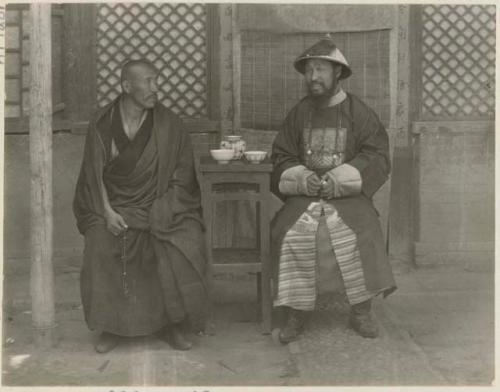 Man in his regalia with one of the head lamas sitting at a small table