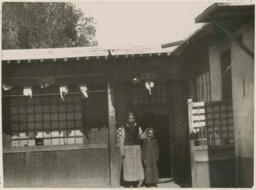 Postal agent with his son in the compound of his shop