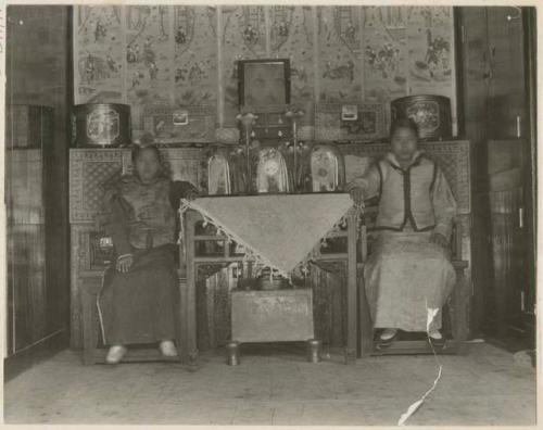 Bride's two sisters sitting by table with wedding gifts