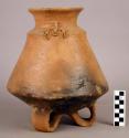 Pottery jar with flaring neck and 3 loop legs and 2 modelled effigy forms on sho