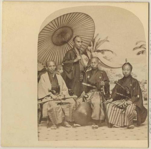 Studio portrait of four men sitting and standing under an umbrella, Japanese delegation visit to New York