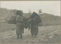 Two Ainu women carrying bundles