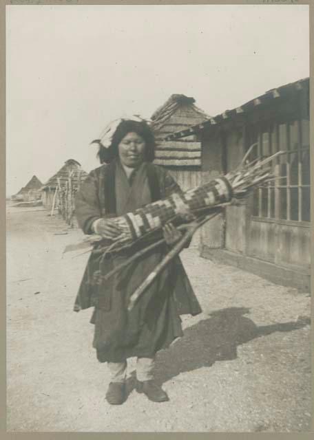 Woman standing in front of buildings holding a bundle