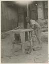 Man constructing stove of wood and mud