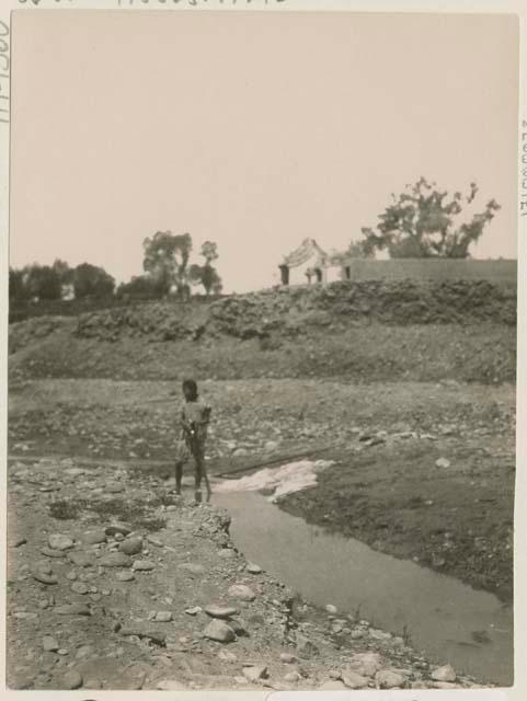 Small boy wading across a brook