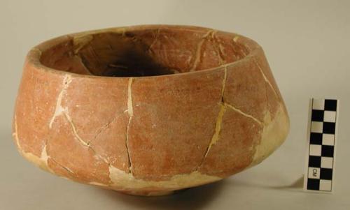 Ceramic bowl, red, incurving sides, flat base, mended and reconstructed.