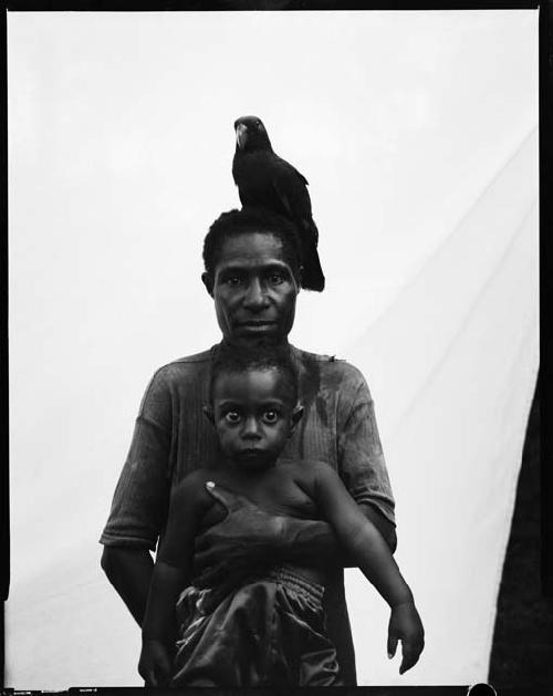 B/W image: Urista Korimbun, Baby Bono Korimbun, and green parrot, Govermas Village, Middle Sepik