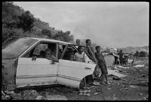 B/W image: Kids inside a wrecked car, Baruni garbage dump, Port Moresby