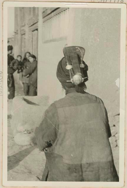 Woman with hairpiece and children in background