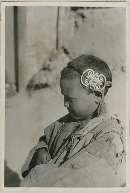 Young boy with pigtail and hair ornament