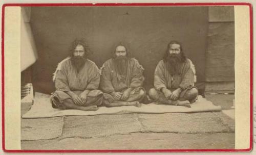 Three men sitting on mat