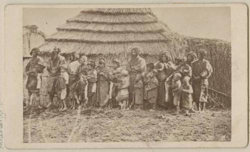 Large group in front of building with thatched roof