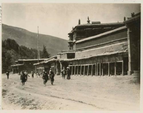 People on road near temples, with prayer wheels