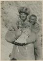 Two men standing outside, one holding prayer wheel