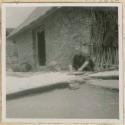 Woman drying cotton outside a building