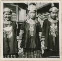 Three girls standing in batik skirts