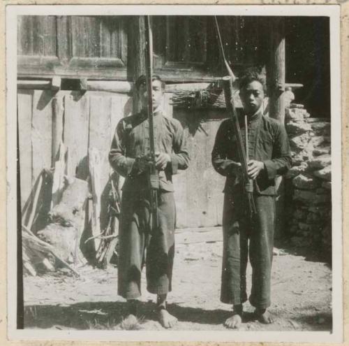 Two boys holding lushengs outside a building