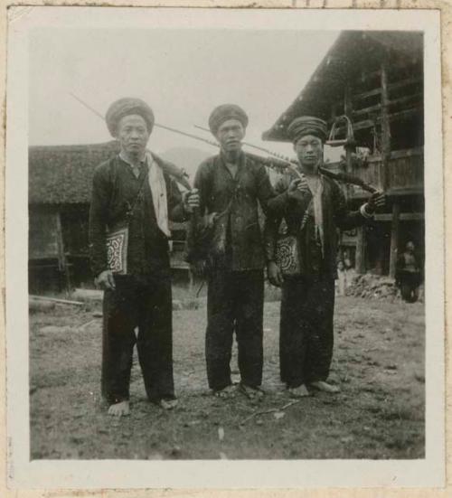 Three men standing outside holding rifles for hunting