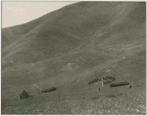 Nomad tents among the hills in the grasslands, with prayer flags hung outside them