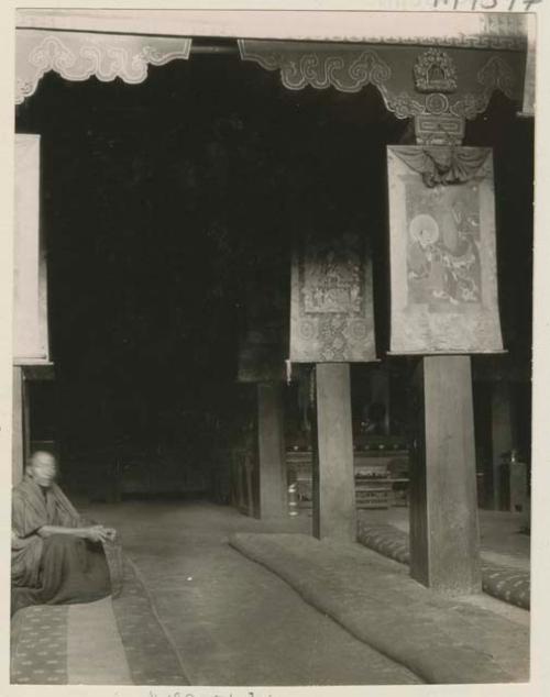 Interior of chanting hall showing seated lama and hangings, Labrang, Tibet