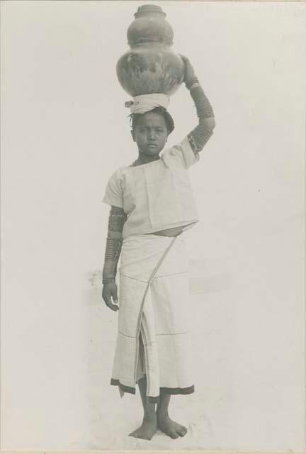 Tinguian woman balancing water vessels on her head