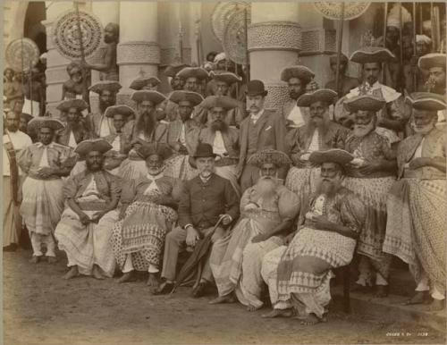 Group in outdoor setting of men with hats by columns