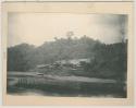 House on the shore with people and canoes in front of it