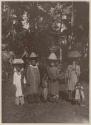 Four women and two children outside, the women in traditional hats