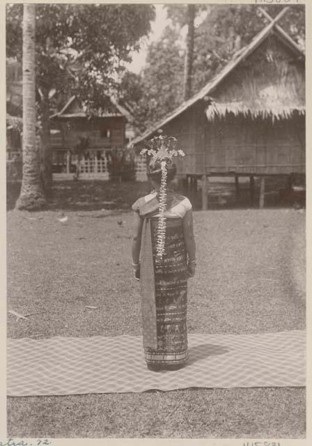 Back of woman standing outside on a mat in traditional dancing dress