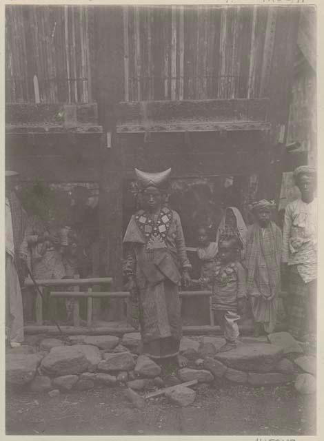 Man standing, with group and structure in background