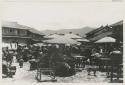Outdoor market with people, tables, and umbrellas