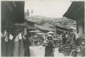 Outdoor market with people, buildings, and goods